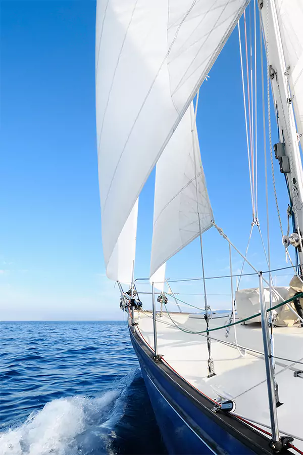 Yacht with the white sails billowing in the wind sailing toward the horizon